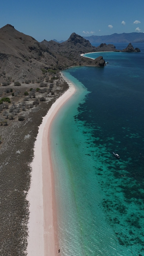 Aerial view of a beach with a gradient of blue water.
