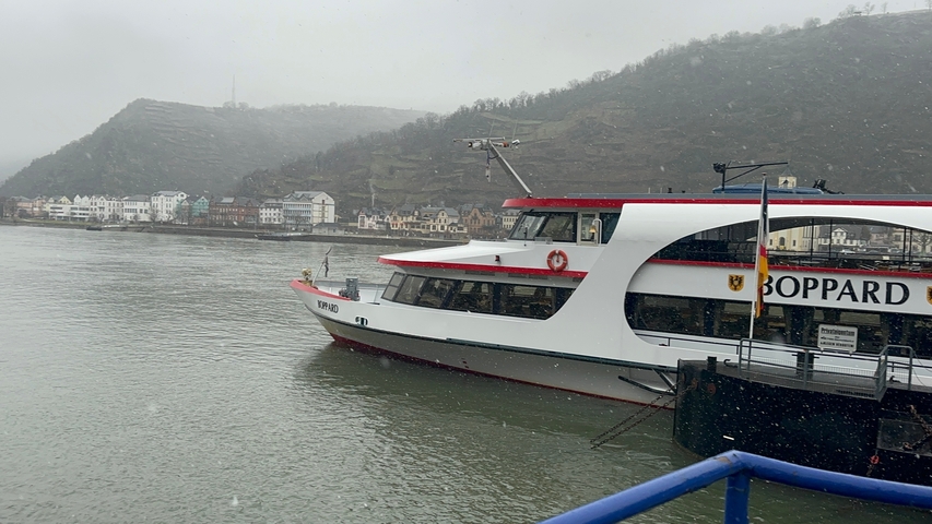 Tourist boat on a river with small town and hills in the background.