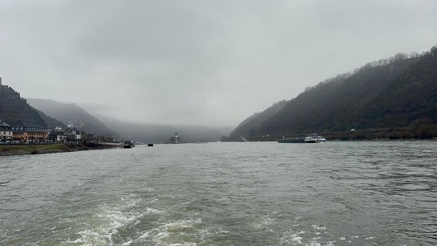 Wide river with overcast sky and hills on either side.