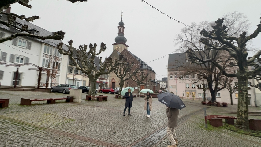 Town square with people holding umbrellas in front of a church.