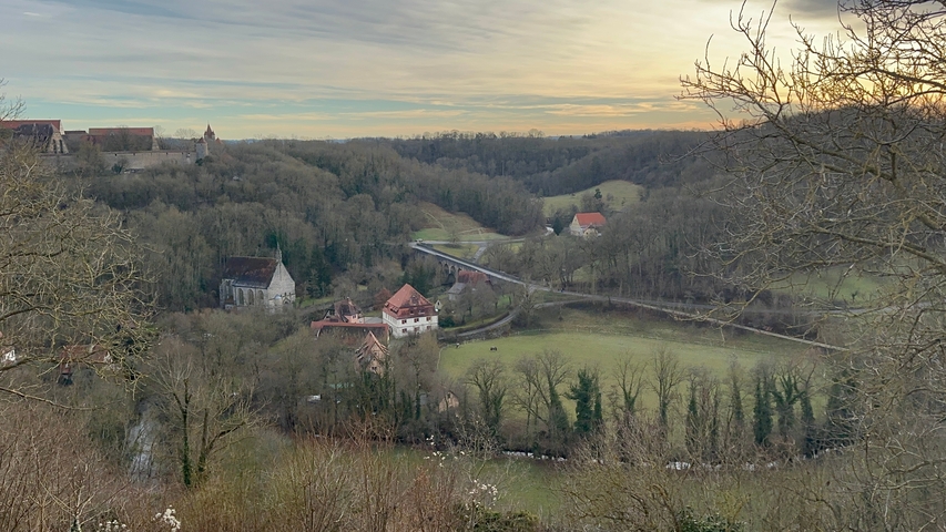 Expansive view of fields and houses with a bridge at sunset.