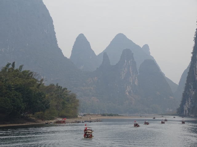       Karst mountains with boats on a misty river.
  