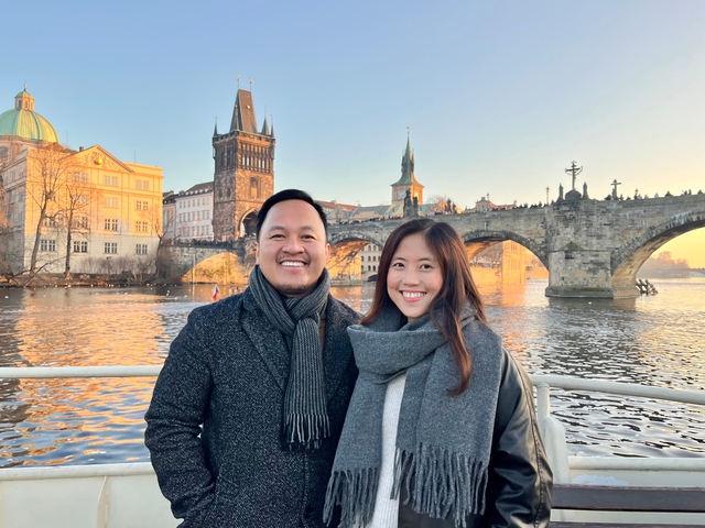 A couple smiling with Charles Bridge in the background.