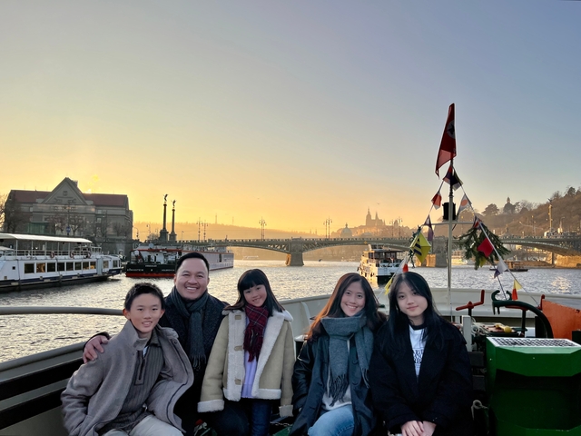 Family on a boat with a cityscape at sunset.