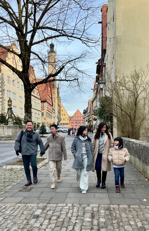 Family walking down a cobblestone street with colorful buildings.