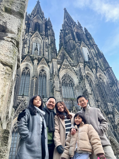 A family posing in front of the Cologne Cathedral.