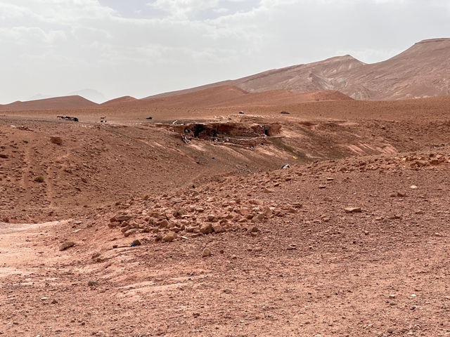Barren desert landscape with small stone structures.