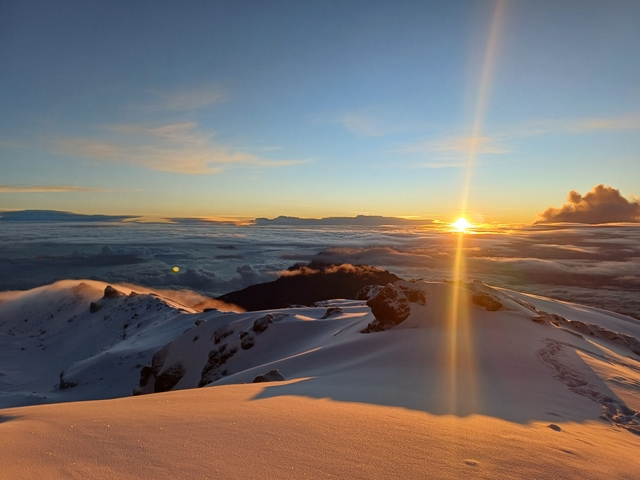 Dramatic sunrise view from a snowy mountain peak.