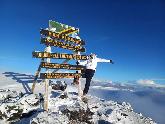 Person posing with a sign on Mount Kilimanjaro.