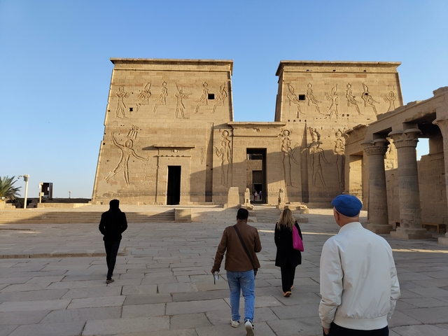 Group of tourists approaching an ancient Egyptian temple.