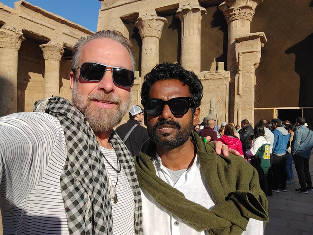       Two men posing for a selfie in front of an ancient Egyptian building.
  