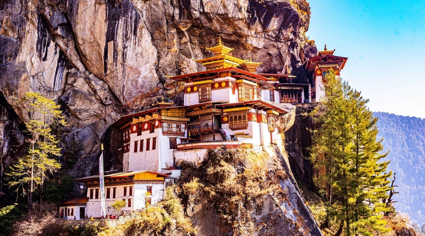 Tiger's Nest Monastery built into a cliff, surrounded by nature, under a clear blue sky.