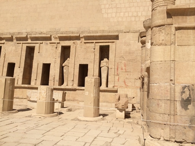 Ancient stone ruins with columns and wall carvings.