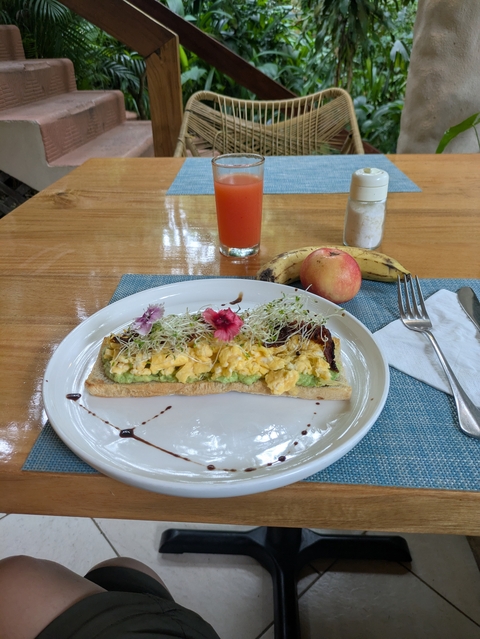       Avocado toast with scrambled eggs on a table setting.
  