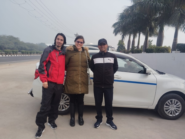       Three people posing in front of a car.
  