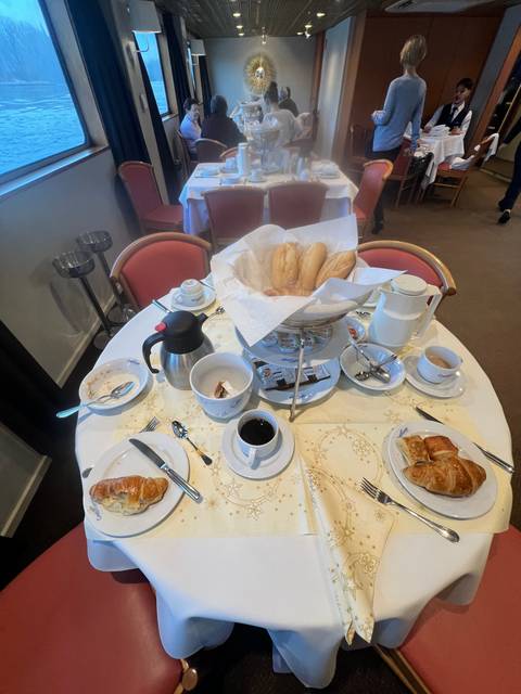 Breakfast table with coffee, pastries, and bread.