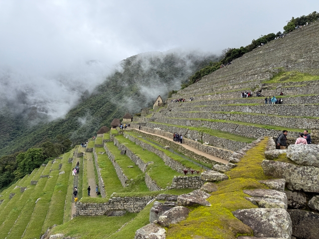       Terraced ruins with people walking on the pathway, surrounded by mist.
  