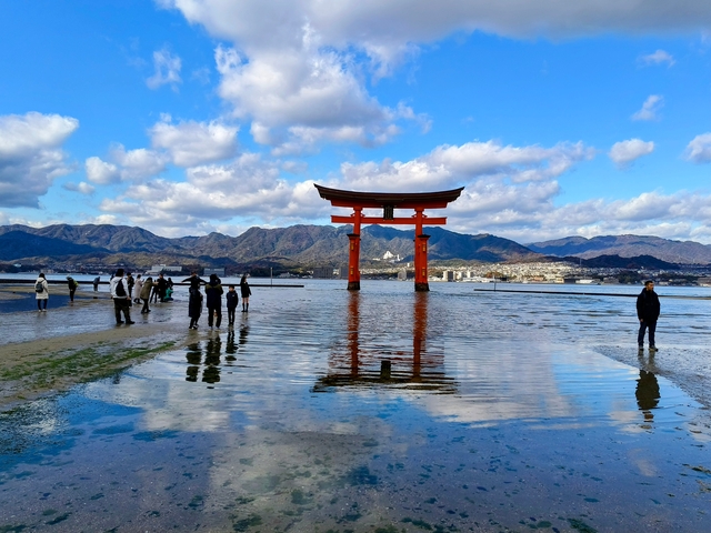       Famous torii gate in the water with mountains in the distance.
  