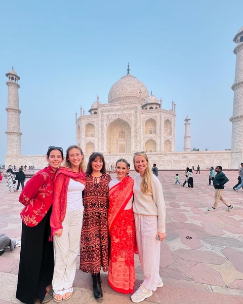       Group of people posing in front of the Taj Mahal.
  