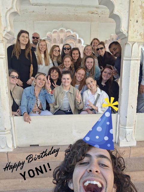       Group of people posing with a giant party hat emoji.
  