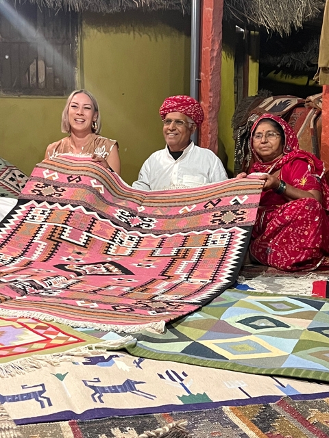       People displaying a traditional carpet.
  