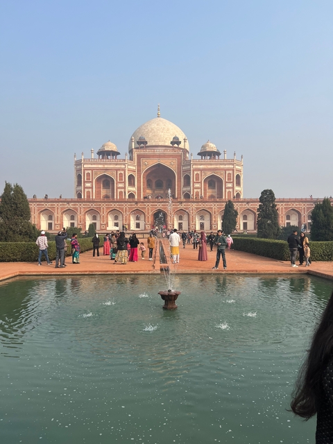       People enjoying a day at a historical site with a water fountain.
  