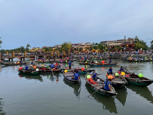 Busy river with boats and people, vibrant town in the background.