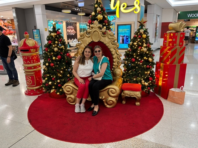       Two people sitting on an ornate chair with Christmas decorations.
  