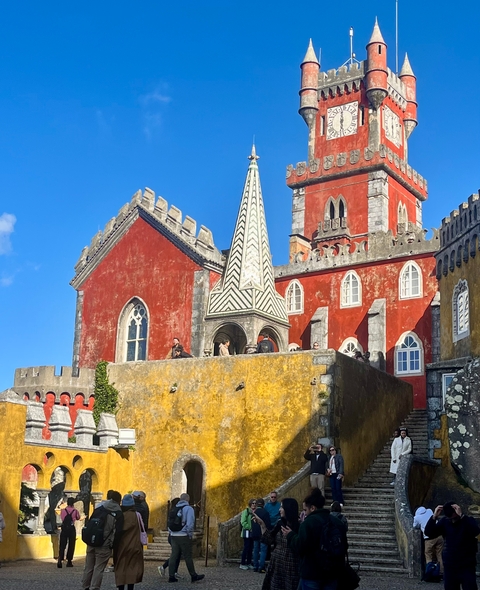       Colorful castle with people on the terrace.
  