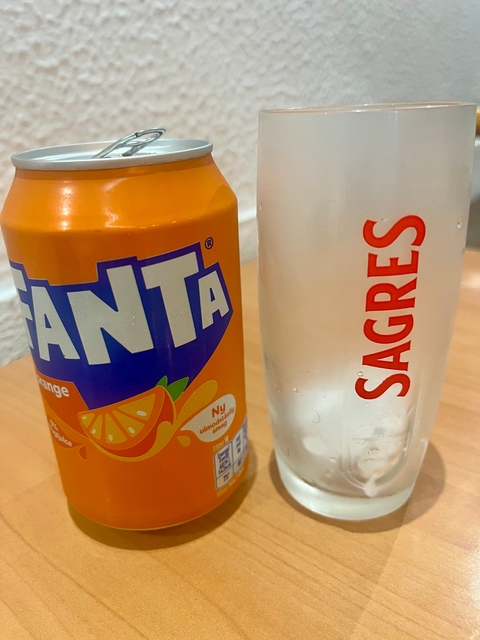       A can of Fanta next to a glass.
  