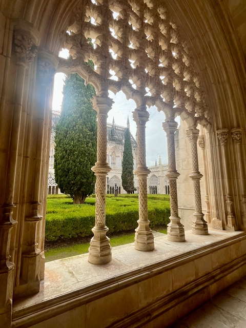       Ornate cloister with greenery and open sky.
  