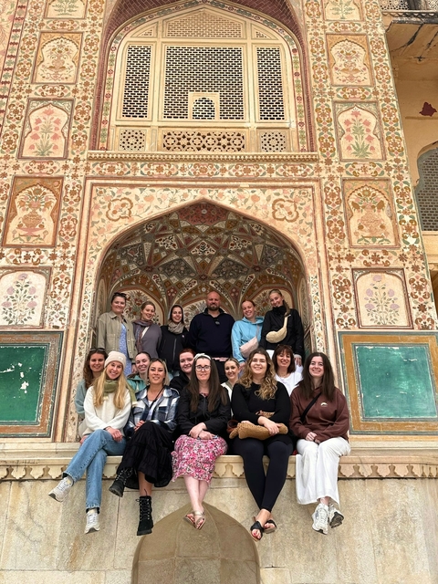       Group of people posing in front of an ornate building entrance.
  