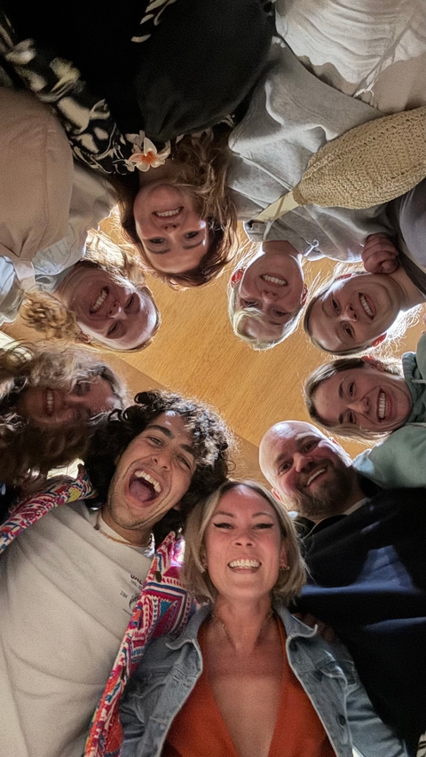       Group of people looking up and smiling in a circle.
  