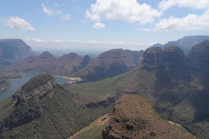       Panoramic view of a mountain range with valleys and a lake.
  
