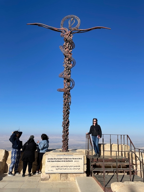 Person posing beside a tall spiral sculpture.