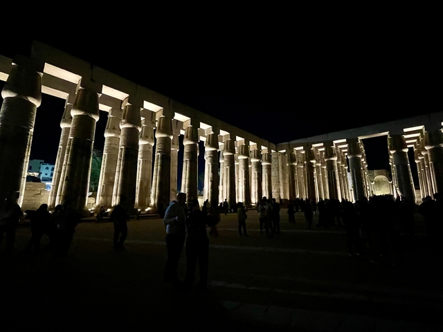 Illuminated columns at night with visitors.
