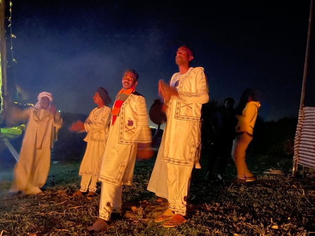       Group of performers in traditional attire singing at night.
  