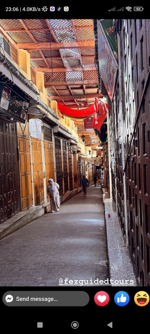       A narrow alleyway in a traditional Moroccan market with people walking through.
  