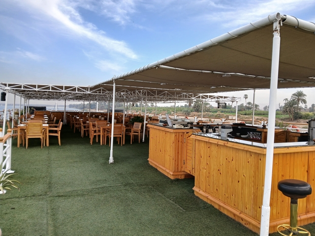 An outdoor dining area with tables and chairs on a boat deck.