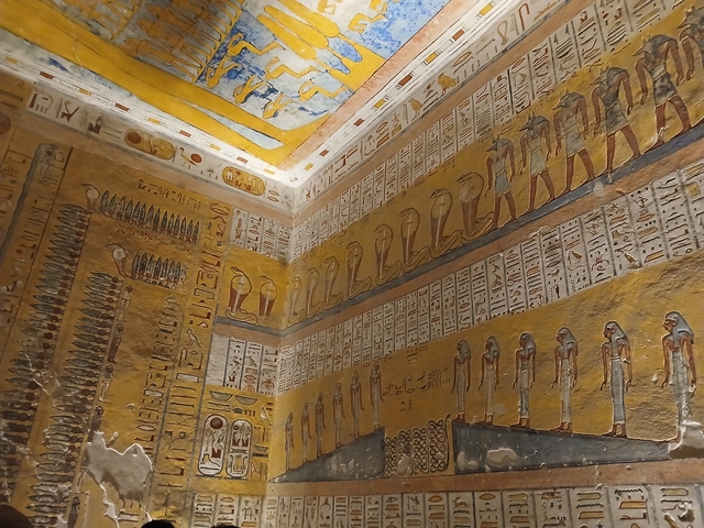 Colorful ancient Egyptian hieroglyphs and paintings on a tomb wall.