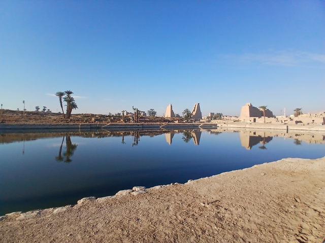 Overview of ancient Egyptian ruins reflected in a water body.