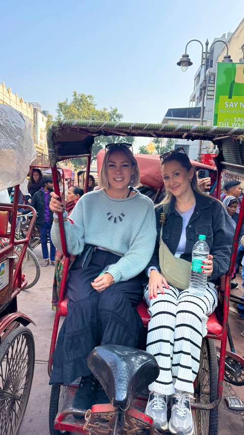       Two people sitting in a rickshaw on a busy street.
  