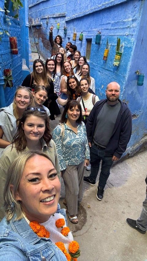       A group of people posing in a blue-painted alleyway.
  