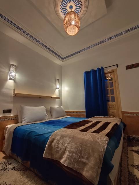 Simple hotel room with a bed and blue curtains.