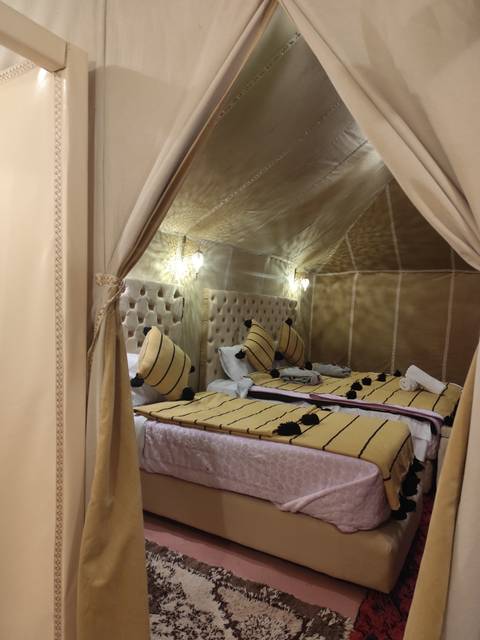 Interior of a luxurious tent with beds and pillows.