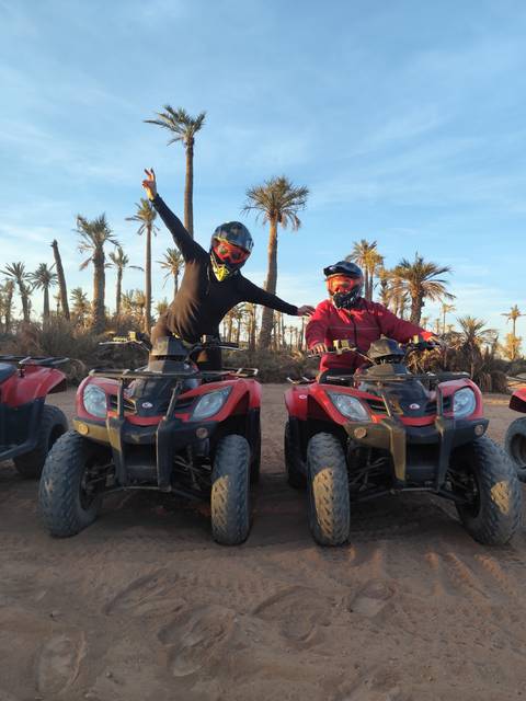       Two people on quad bikes posing in a desert location.
  