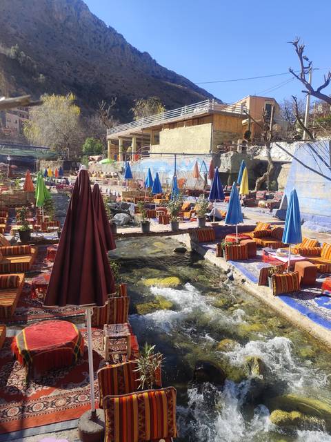 Outdoor seating setup with colorful decor near a stream.