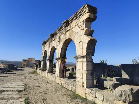       Person standing among ancient stone arches.
  