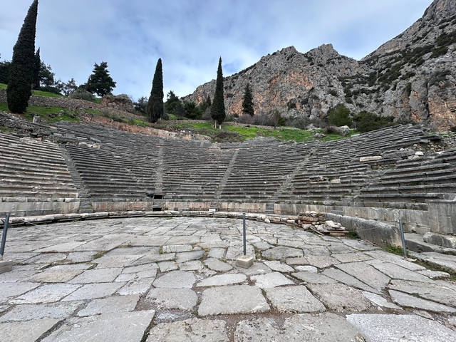       Ancient amphitheater with mountains in the background.
  