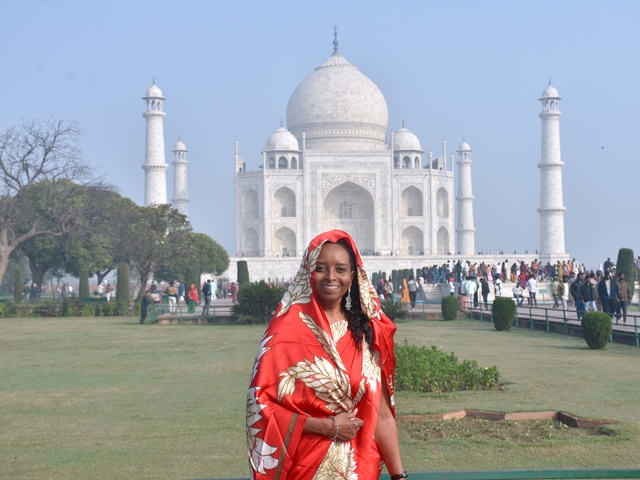 Woman in red attire in front of the Taj Mahal.